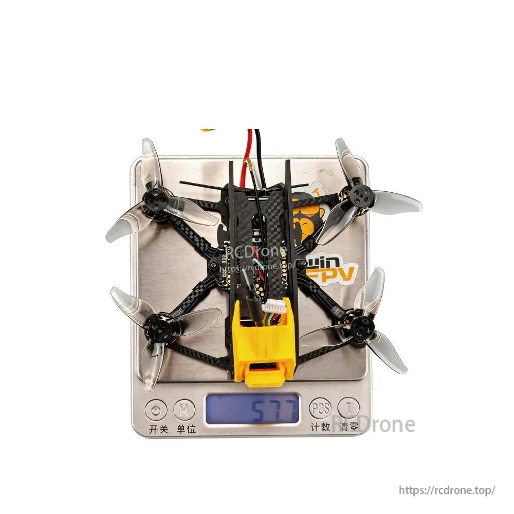 Top view of quadcopter on digital scale showing weight reading 57.7 g