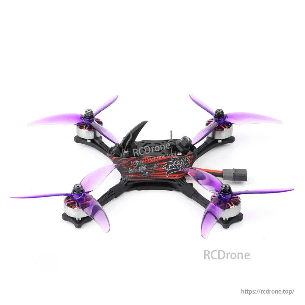 Rear/top view of quadcopter showing strap mount, battery lead, carbon frame arms, and purple tri-blade props