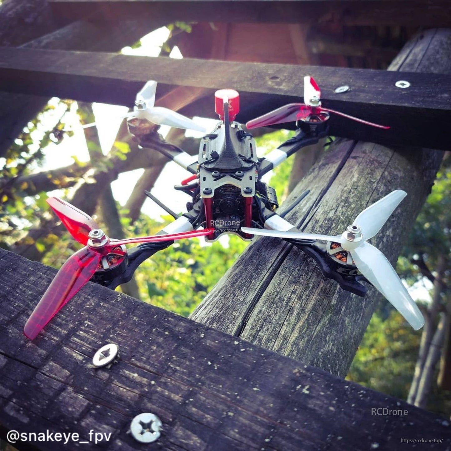 Red and white Ethix P4 3-blade props installed on a quadcopter frame outdoors, top-down view