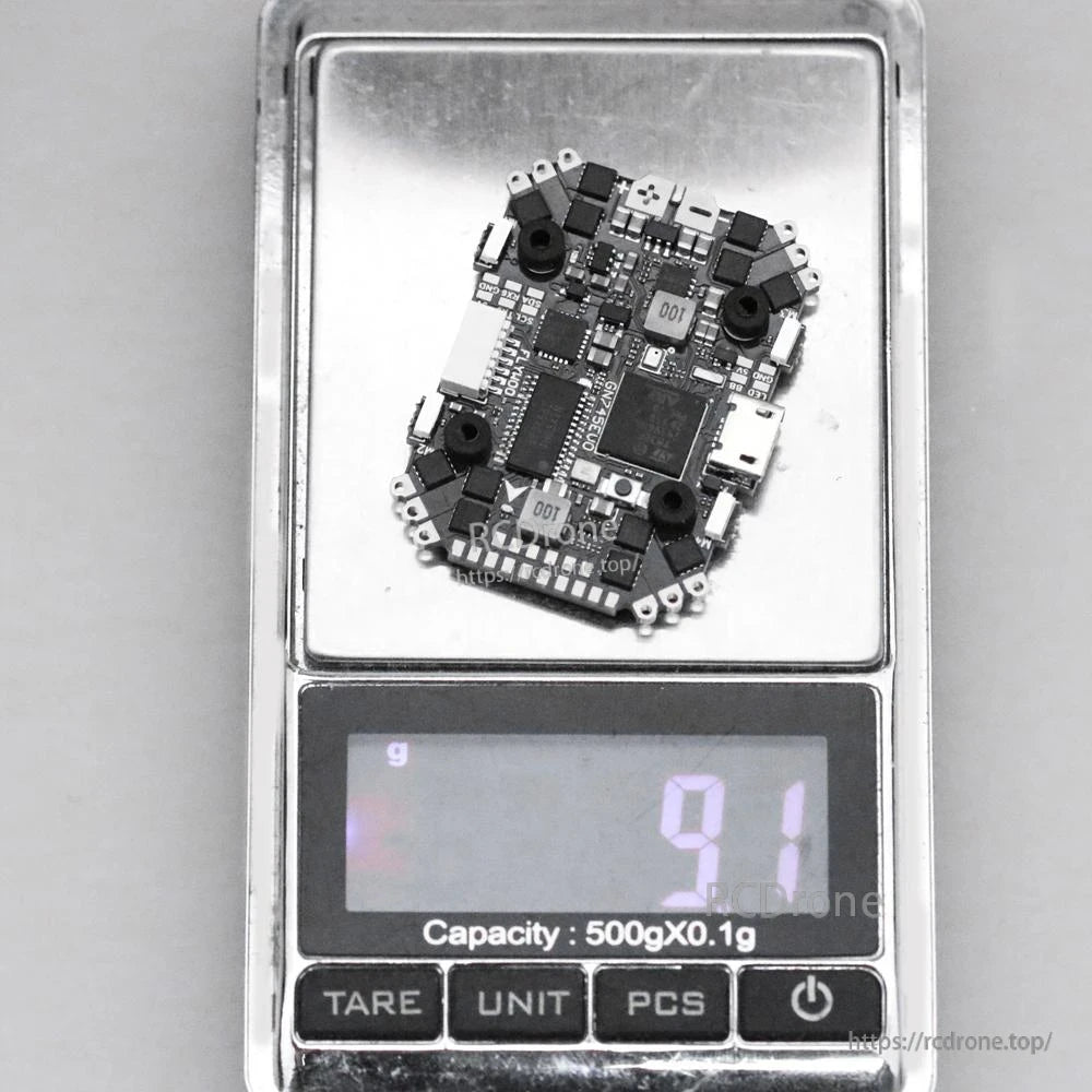 Flywoo GOKU HD745 EVO 20x20 AIO flight controller on a digital scale, showing about 9 g weight and USB port