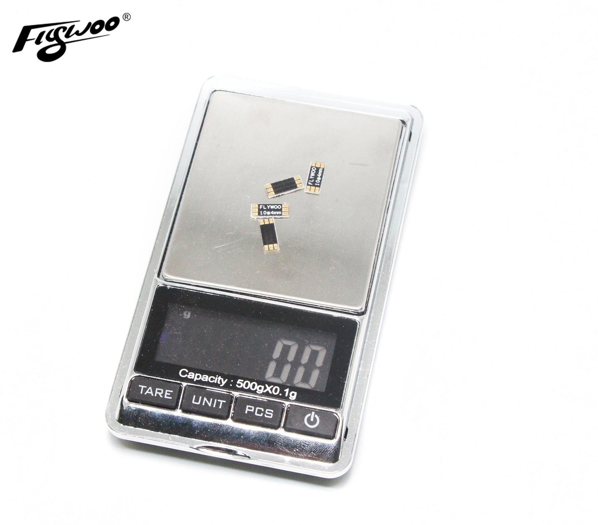 Small Flywoo frame arm boards on a digital scale, with gold pads and “FLYWOO 10×4mm” marking.