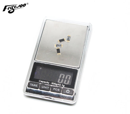 Small Flywoo frame arm boards on a digital scale, with gold pads and “FLYWOO 10×4mm” marking.