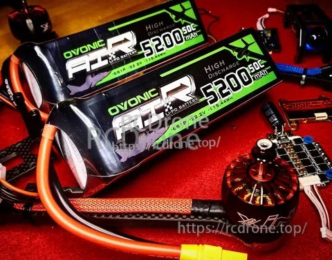 Two Ovonic 6S 5200mAh 50C LiPo batteries on an RC workbench with EC5 leads and electronics nearby