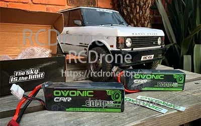 Two Ovonic 8000mAh 3S 50C LiPo battery packs with decals and box in an outdoor RC car setup
