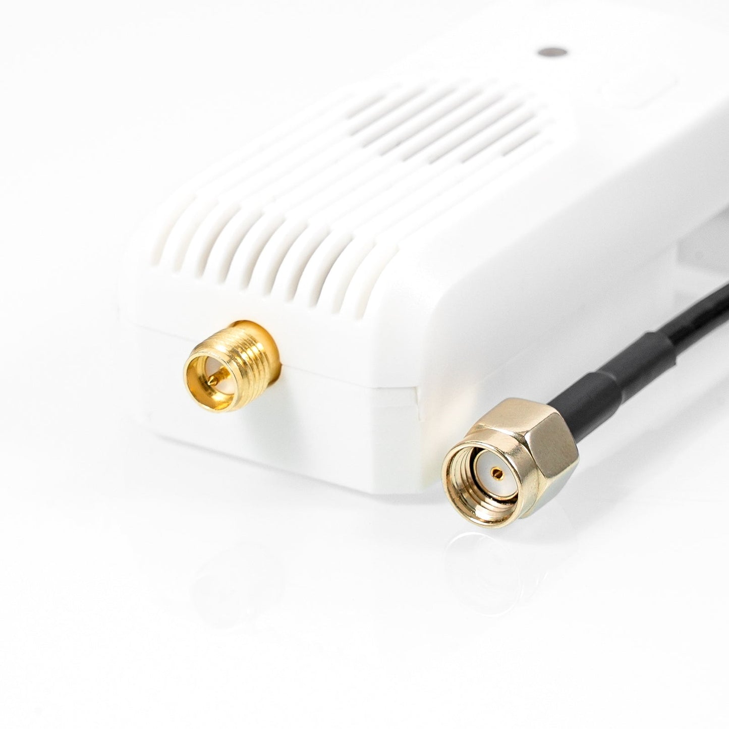 Close-up of gold antenna connector on module with attached coax lead and threaded RF fitting
