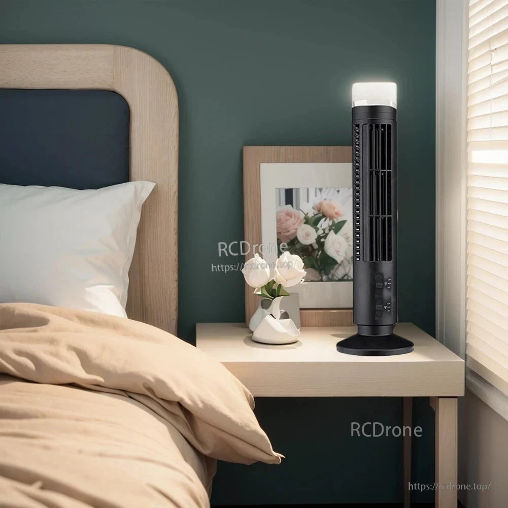 Black tower fan with LED light on, placed on bedside table near window and lamp
