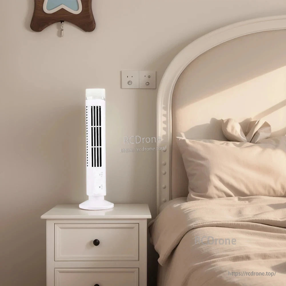 White tower fan with LED light glowing on nightstand next to bed in bright bedroom