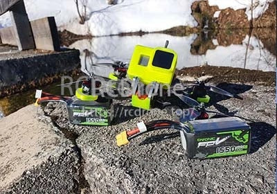 Ovonic 1550mAh 4S LiPo batteries next to an FPV drone and action camera with XT60 plugs