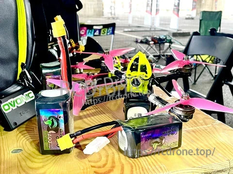 Two Ovonic Rebel 2.0 6S LiPo packs with XT60 leads beside a 5-inch FPV quad on a workbench