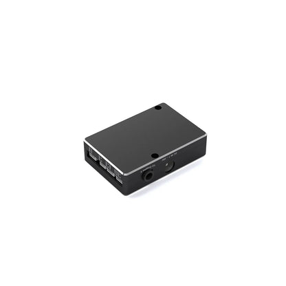 Extension module bottom-side angled view with smooth cover, side mounting holes, and labeled port edge