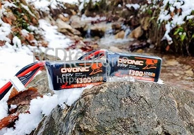 Ovonic 6S 1300mAh 120C LiPo battery with XT60 lead and balance connector on rock outdoors