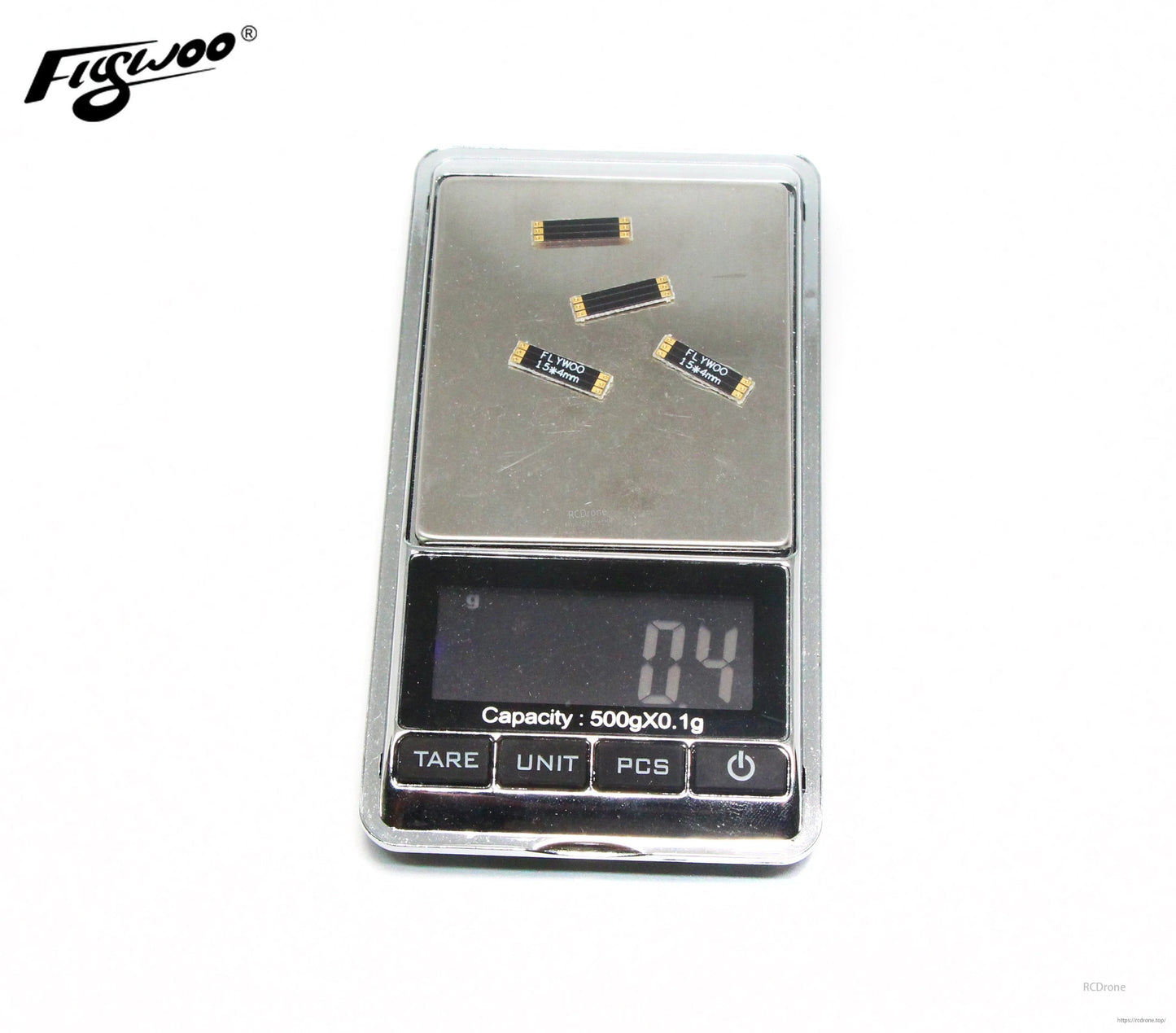 Four Flywoo frame arm boards labeled 15x4mm with gold pads, placed on a digital gram scale