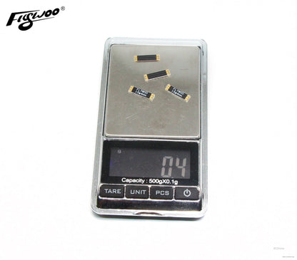 Four Flywoo frame arm boards labeled 15x4mm with gold pads, placed on a digital gram scale
