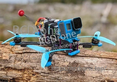 Compact FPV quadcopter setup resting on a log, illustrating battery fitment for freestyle builds
