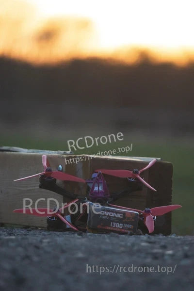 FPV quadcopter with an Ovonic 6S 1300mAh 120C LiPo pack placed beside the frame at sunset