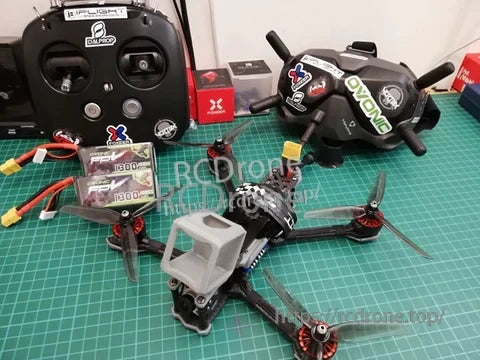 Ovonic 4S 1300mAh 14.8V LiPo packs on an FPV workbench beside a quadcopter and radio gear