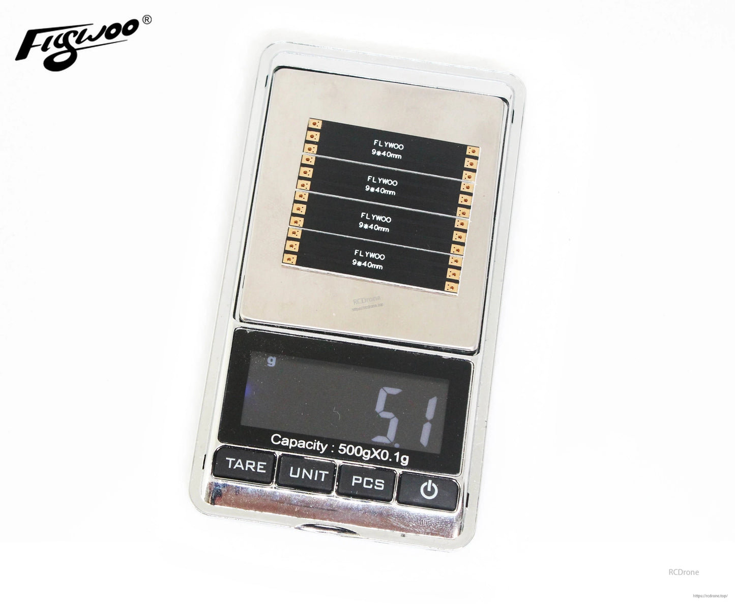 Four Flywoo 9x40mm FPV drone frame arm boards with solder pads displayed on a digital pocket scale