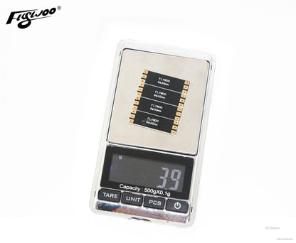 Flywoo FPV drone frame arm board set on a digital scale, showing 7.9 g weight and labeled solder pads.