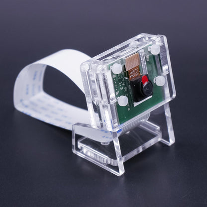 Clear acrylic camera case on display stand, angled view with CSI ribbon cable looped behind