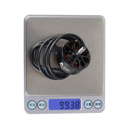 Flashhobby A3210 800KV brushless motor with long lead wires, sitting on a digital scale reading 99.38 g