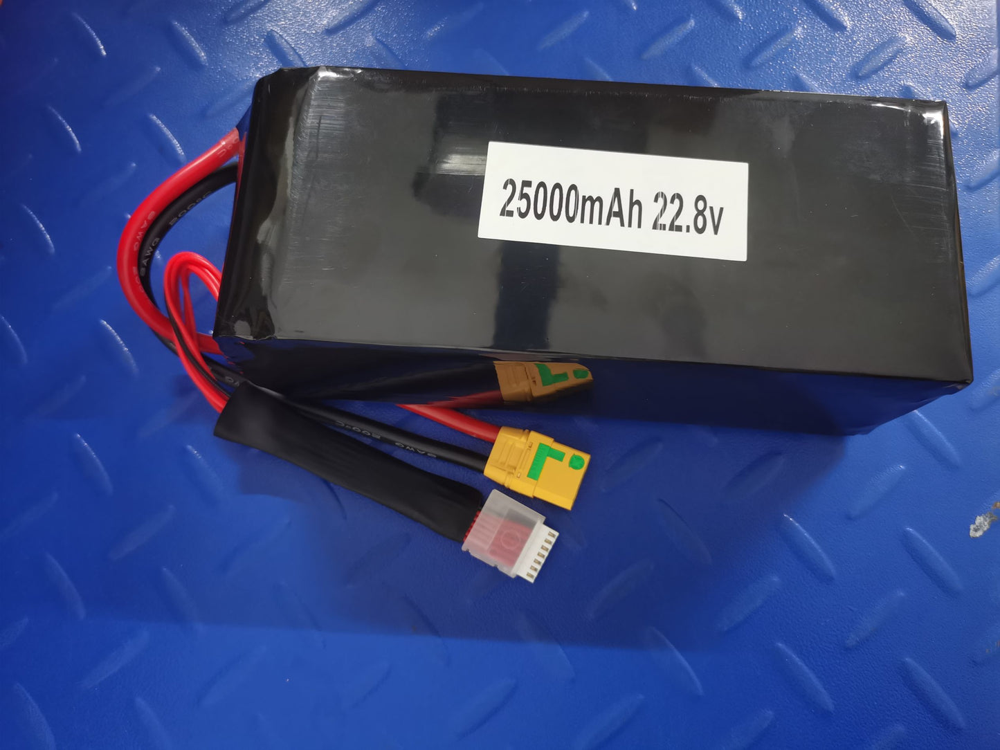 Top view of battery pack with sticker "25000mAh 22.8v" and attached power and balance leads