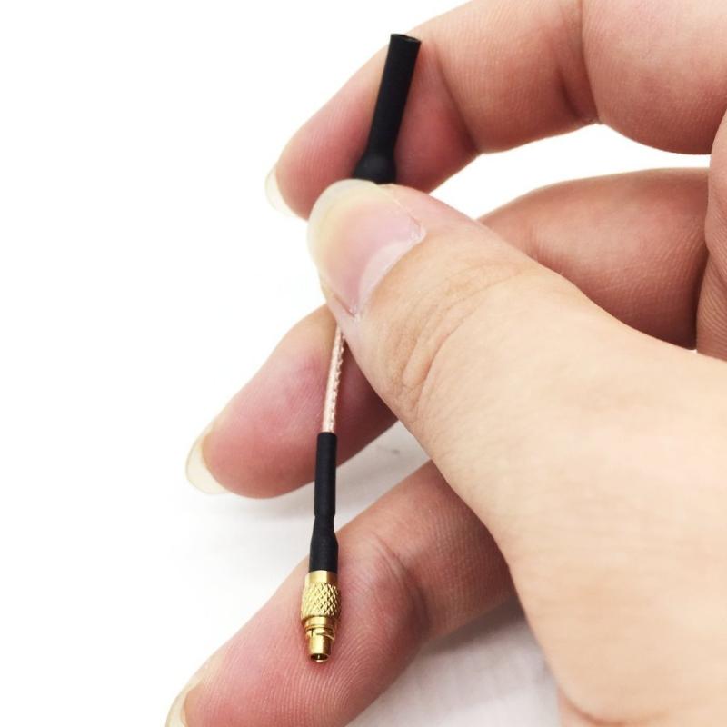 Hand holding compact 80mm FPV antenna with gold MMCX-J connector to show size and cable thickness