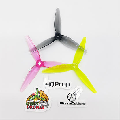 Top view of 5 inch tri-blade drone propellers in pink, smoke gray and neon yellow with HQProp PizzaCutters stickers
