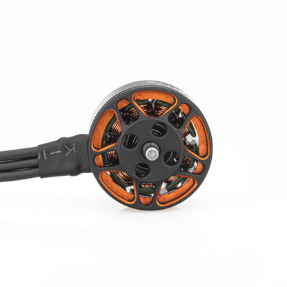 Top view of SPARK 1104 brushless motor bell with orange cutouts, center shaft, and motor wires