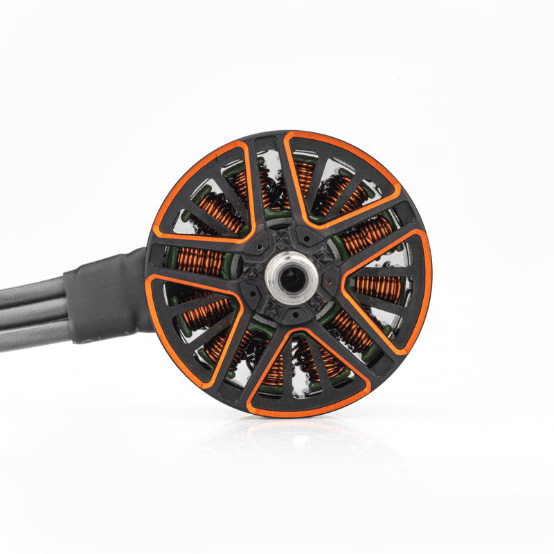 Top view of brushless motor bell with orange cutouts, copper windings, and lead wires