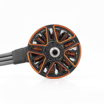 Top view of brushless motor bell with orange cutouts, copper windings, and lead wires