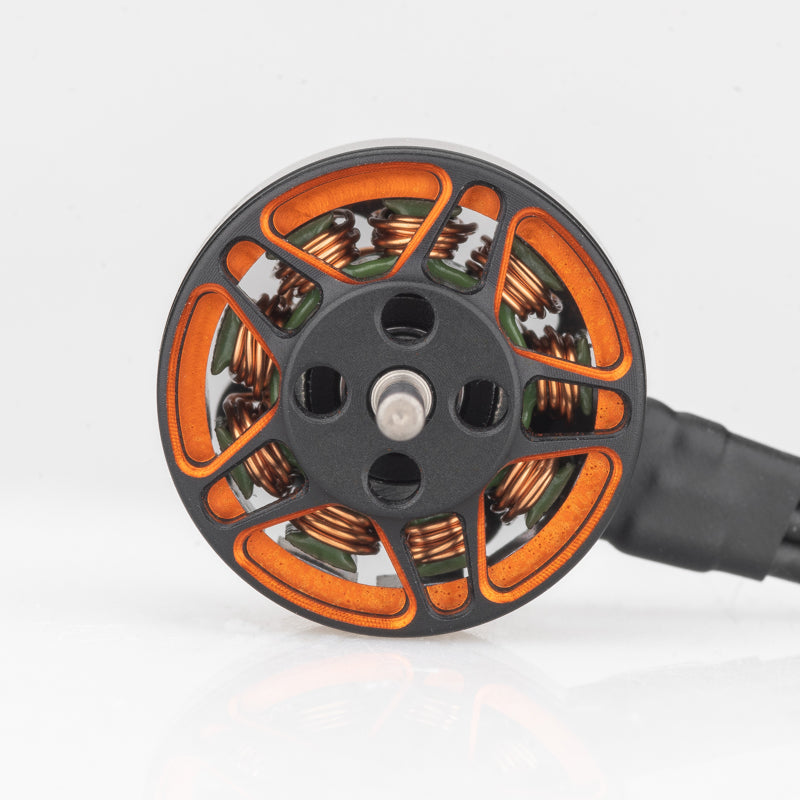 Top view of 1203 brushless motor bell showing orange cutouts, center shaft, and copper windings