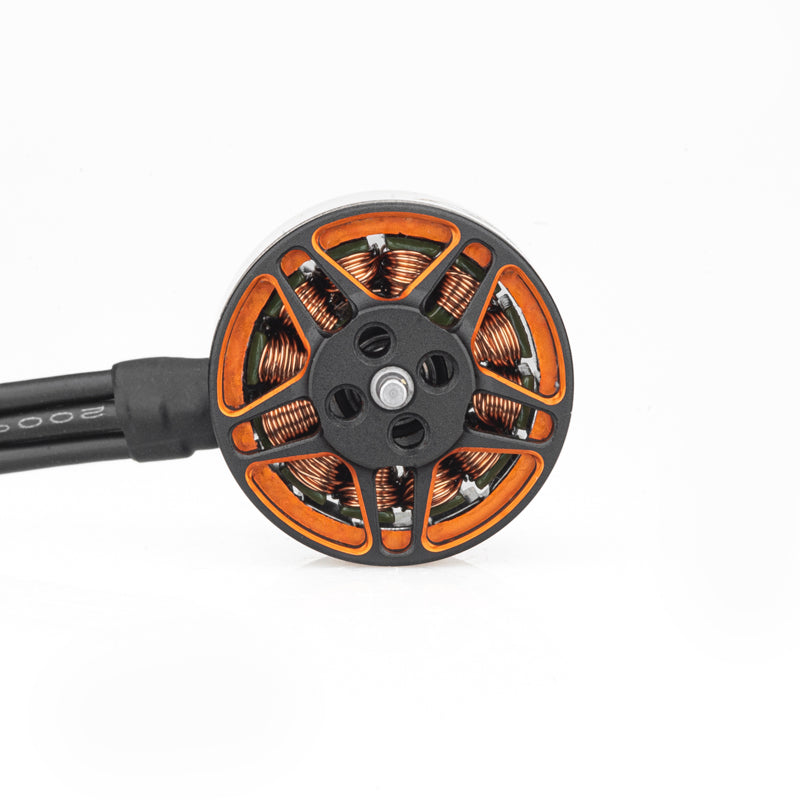 Top view of brushless motor rotor showing copper windings, orange cutouts, and attached power leads
