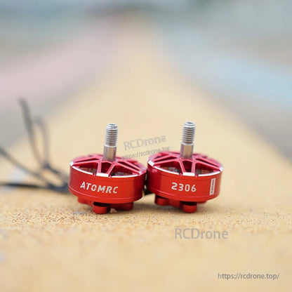 Two red ATOMRC 2306 brushless motors side by side, showing printed “ATOMRC” and “2306” on the bell