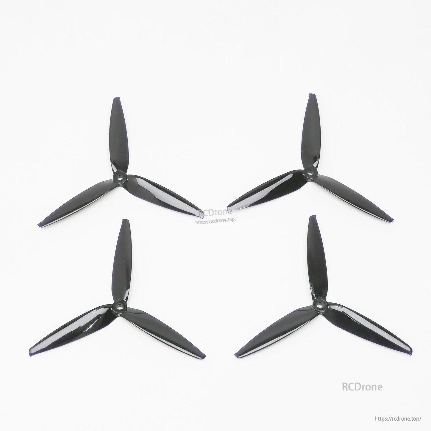 Set of four black tri-blade propellers for ATOMRC Beluga fixed wing, laid out on white background
