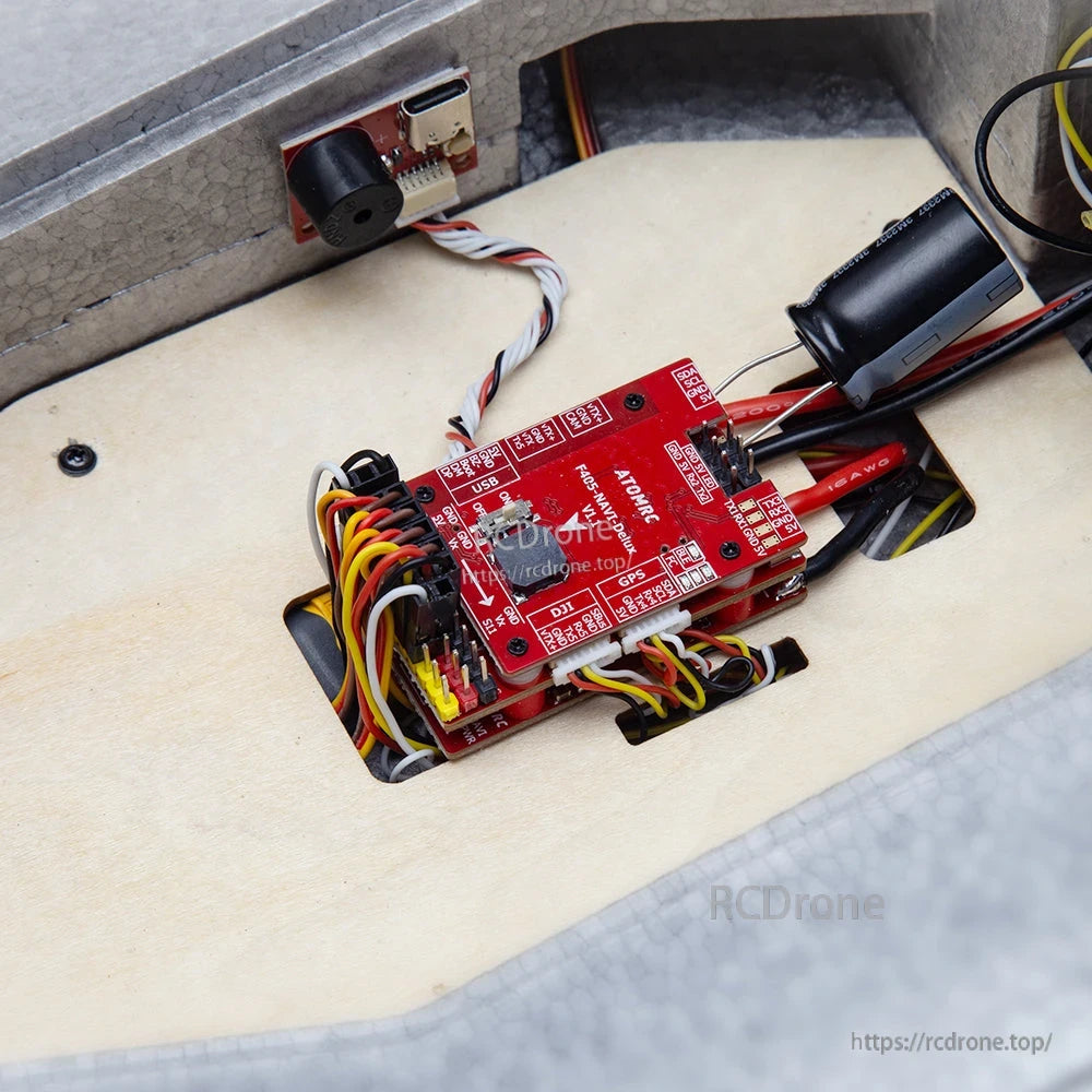Flight controller installed inside RC plane fuselage with wiring harness connected and electronics bay view