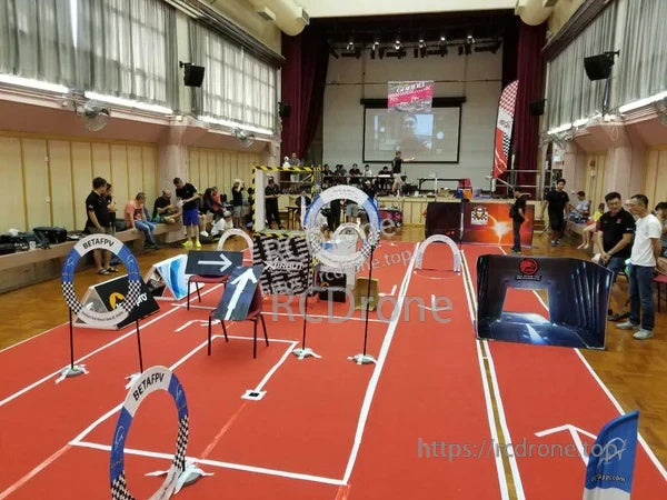 Indoor micro FPV race course setup with multiple gates and flags, including the BETAFPV arch gate