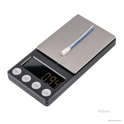 Short cable with white plug on digital scale reading 0.94 g, close-up weight view