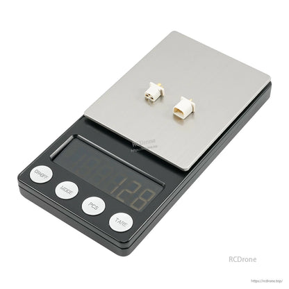Two white connector parts placed on a digital scale, showing combined weight