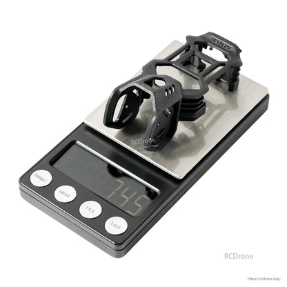 Camera canopy bracket set on scale showing 7.9 g weight, angled view