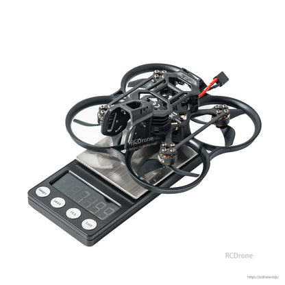 BetaFPV ducted cinewhoop quadcopter on a digital scale, showing compact frame with prop guards and battery lead