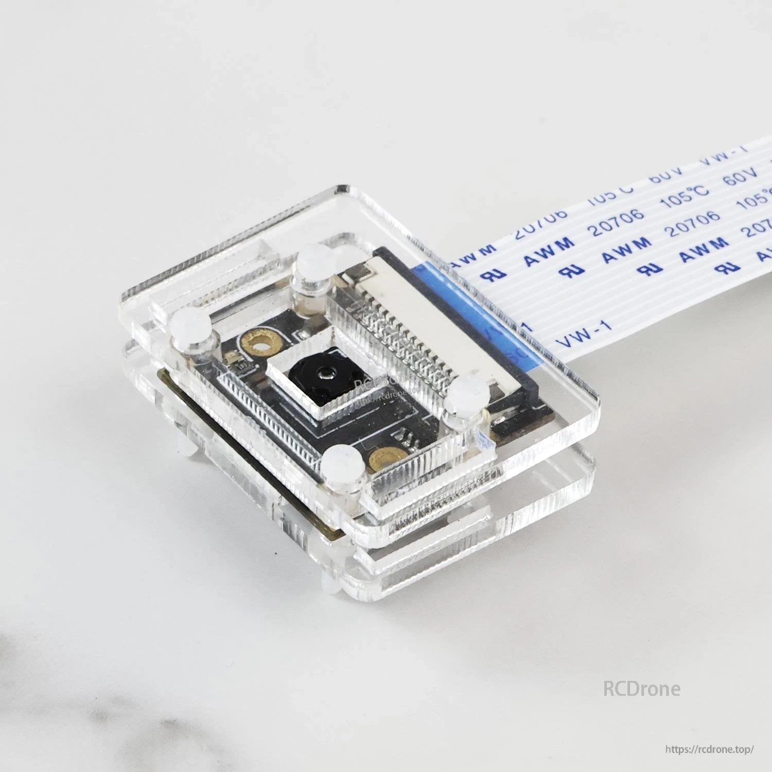 Top view of camera module in clear acrylic housing, showing CSI ribbon connector and mounting screws