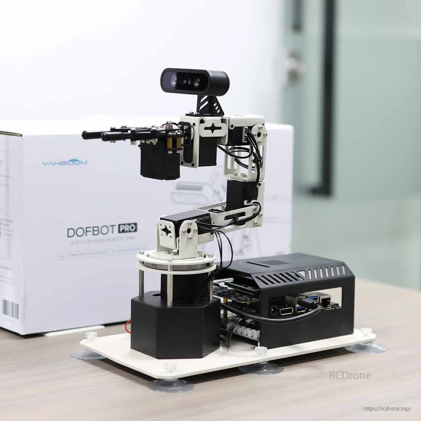 DOFBOT Pro robotic arm on base with depth camera, shown next to product box in a clean desktop scene