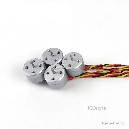 Set of four micro brushless motors with twisted lead wires grouped together on white background