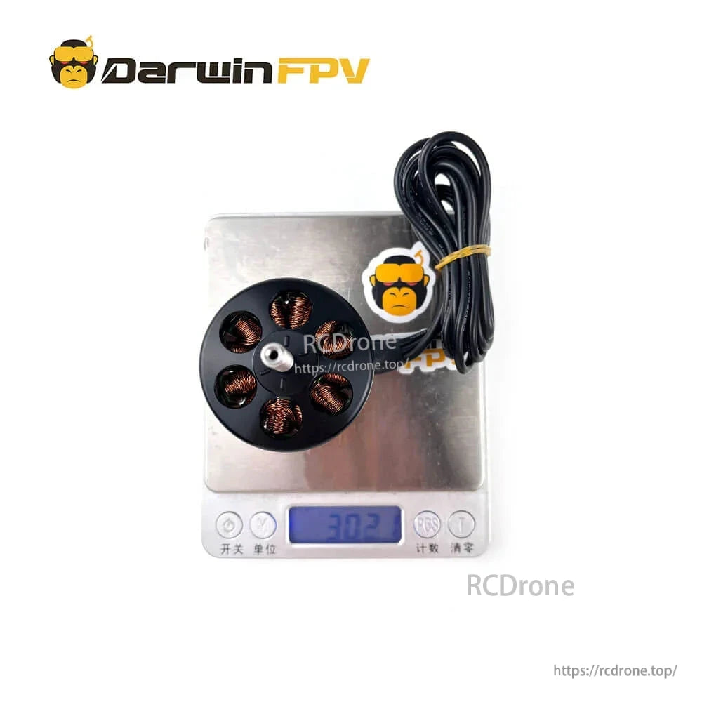 Motor placed on digital scale with display reading 302, lead wires coiled beside the unit