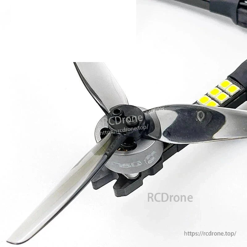 Motor and tri-blade propeller close-up on drone arm with LED strip detail