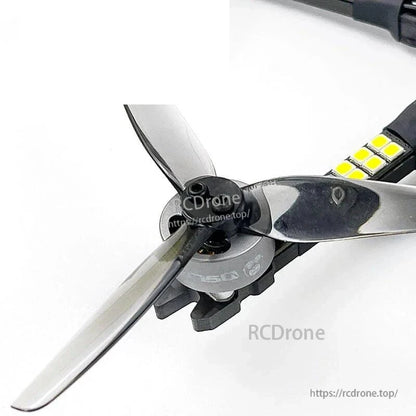 Motor and tri-blade propeller close-up on drone arm with LED strip detail