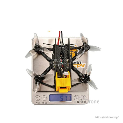 Top view of quadcopter on digital scale showing weight reading 57.7 g