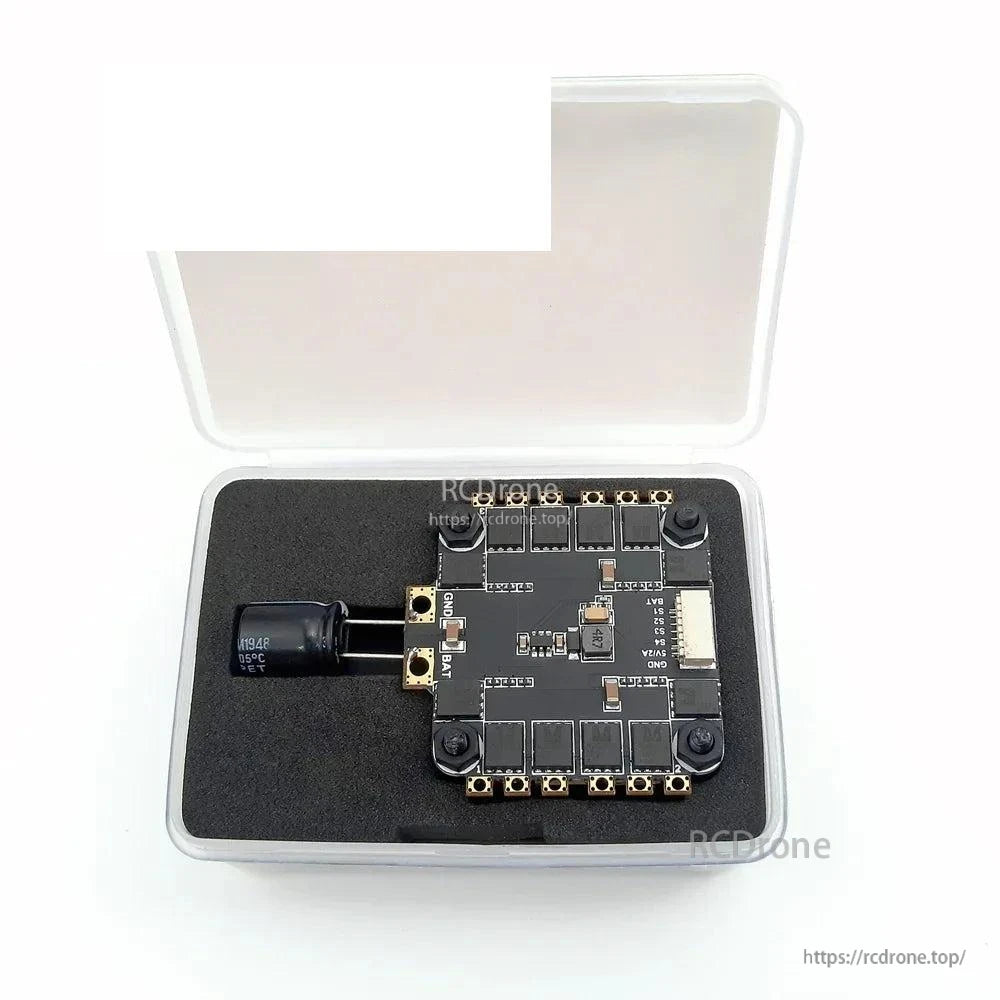 Flight controller kit stored in clear plastic case with foam insert and capacitor beside the board