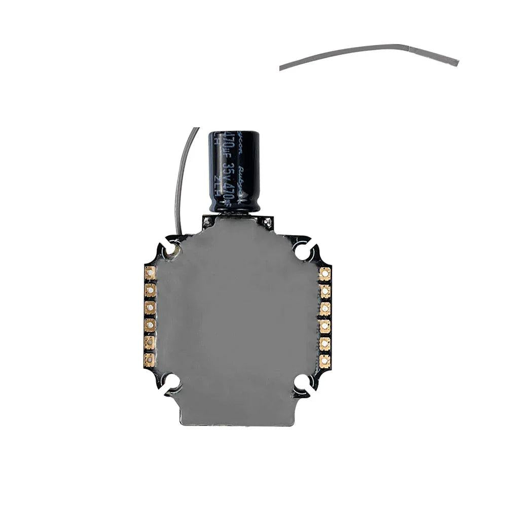 AIO flight controller stack rear view showing metal RF shield, solder pads, and attached capacitor lead