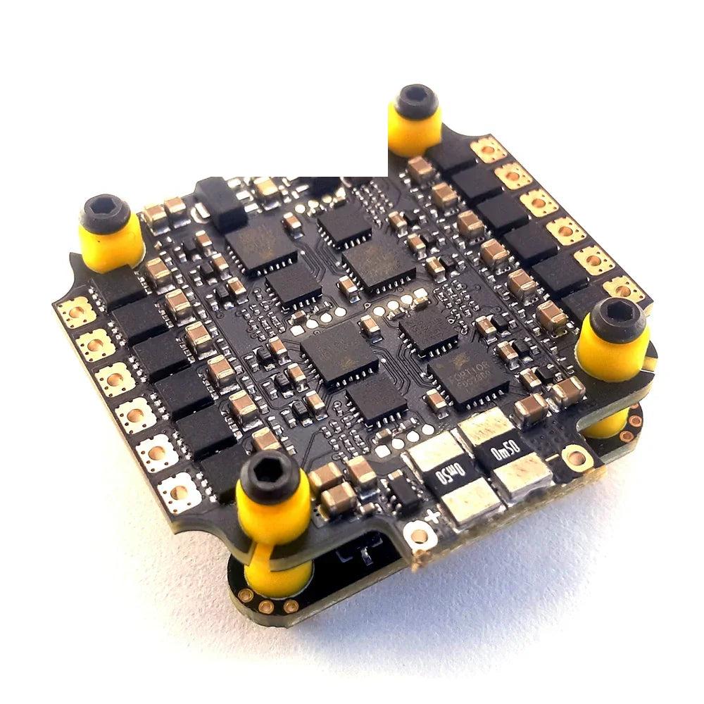 Whoop stack ESC board close-up showing MOSFET layout and yellow soft-mount corners